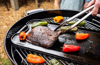 Beef steak grilling on a barbecue with colorful peppers nearby, tongs lifting the meat outdoors.