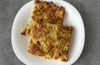 Overhead view of several slices of veggie frittata on a white plate against a dark countertop felt surface.