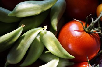 Close-up of fresh green okra pods and ripe red tomatoes in a vegetable basket.